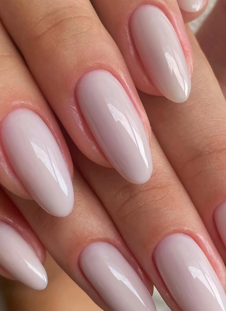 Mãos com alongamento de unhas natural em tom nude sobre seda champagne